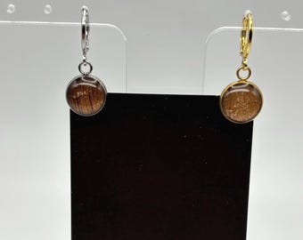 Puede incluir: Un par de pendientes con un diseño circular de madera. Un pendiente tiene un aro plateado y el otro un aro dorado. Se exhiben frente a una tarjeta negra con el texto "MIDNIGHT TIMBER CO."