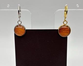 Puede incluir: Un par de pendientes redondos con un diseño de vetas de madera. Un pendiente tiene un aro plateado y el otro un aro dorado. Los pendientes se exhiben en una tarjeta negra con la palabra "MIDNIGHT" en la parte inferior.