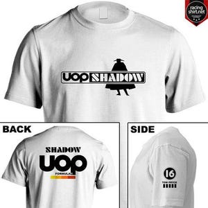 Puede incluir: Camiseta blanca con un gráfico negro de una figura y el texto "UOP SHADOW". La parte trasera de la camiseta presenta "SHADOW UOP FORMULA" en negro y amarillo. El lateral muestra "16 TOM PRYCE" en negro.