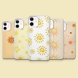 May include: Five clear smartphone cases arranged in a row, each featuring a unique sun-themed pattern. The designs include various yellow, orange, and brown sun illustrations, ranging from simple line drawings to detailed motifs on different backgrounds.