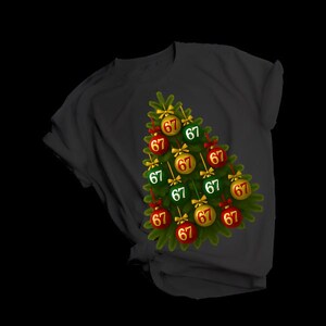 May include: A black t-shirt with a Christmas tree design. The tree is made of green branches and decorated with red and gold baubles, each showing the number "67". Gold bows are on top of each bauble.