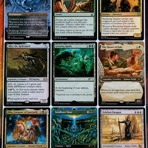 May include: A collection of nine Magic: The Gathering trading cards arranged in a three-by-three grid. The cards feature various fantasy illustrations, text descriptions, and game mechanics, including Mirari's Wake, Druid's Deliverance, Wayfaring Temple, Rhys the Redeemed, Growing Ranks, The Queen of Dale, Elda, Conjurer of Spectacle, Seedborn Muse, and Nykthos Paragon.