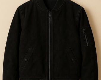 May include: Black bomber jacket with a zip-up front, two front pockets, and a zippered pocket on the left sleeve. The jacket has a ribbed collar, cuffs, and hem. The jacket is hanging on a wooden hanger.