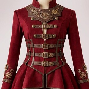 May include: A deep red long-sleeved jacket featuring a high collar, a front zipper, and four horizontal brown buckled straps across the torso. The jacket has a high-low hemline, brown trim, and decorative metallic gear accents on the chest and cuffs.