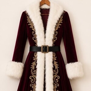May include: A long, deep burgundy velvet coat featuring a thick white faux fur trim along the collar, cuffs, and hem. The front panels are decorated with intricate gold embroidery in a scrolling pattern, and a black belt with a buckle is included.