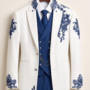 May include: A white long coat featuring intricate blue floral embroidery on the lapels, sleeves, and lower front. The coat is paired with a blue vest, a white collared shirt, a blue necktie, and blue trousers, complete with a silver chain detail.