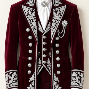 May include: A deep burgundy velvet tailcoat and matching vest featuring intricate silver floral embroidery along the lapels, cuffs, and hem. The set includes silver buttons, a white cravat with a crystal brooch, and a silver chain accessory.