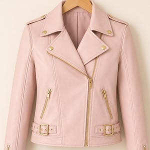 May include: Pale pink faux leather biker jacket with gold-tone metal hardware. The jacket has an asymmetrical zip, notched lapels, and a belt at the waist. Zips are present on the sleeves. A stylish outerwear garment.