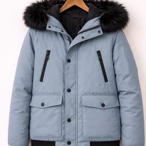 May include: A pale blue winter jacket with a black fur-trimmed hood. The jacket has a black lining, black zips, and black buttons. It features two front pockets and a black ribbed hem.