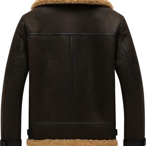 May include: A brown leather jacket with a tan shearling collar and lining. The jacket has a classic design with a button closure at the cuffs and a vertical seam detail on the back. The jacket is hanging on a black hanger.