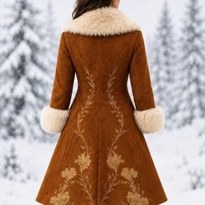 May include: A long, brown, suede-like coat featuring a cream-colored faux fur collar and matching cuffs. The back of the coat is decorated with intricate, light-colored floral embroidery that extends from the waist down to the hemline.