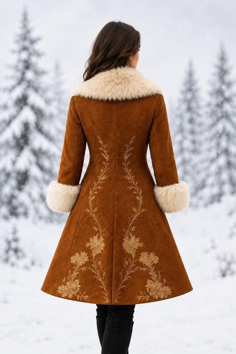 May include: A long, brown, suede-like coat featuring a cream-colored faux fur collar and matching cuffs. The back of the coat is decorated with intricate, light-colored floral embroidery that extends from the waist down to the hemline.