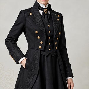 May include: A black long-sleeved coat with a high collar, featuring gold-toned buttons, intricate tonal embroidery on the lapels and cuffs, and a matching waistcoat worn over a white shirt with a black cravat secured by an ornate gold brooch.