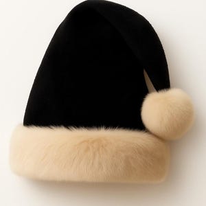 May include: A black Santa-style hat featuring a thick, cream-colored faux fur trim around the base and a matching cream-colored faux fur pom-pom attached to the tip of the folded top. The hat has a smooth, solid black fabric construction.