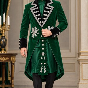 May include: A dark green velvet long coat featuring black velvet lapels and cuffs, silver embroidery of griffins, and silver buttons. The coat is worn over a matching green tunic with a central vertical panel of silver buttons and embroidery, paired with black trousers.