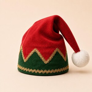 Puede incluir: Un gorro de fieltro rojo y verde con un patr&oacute;n en zigzag en el centro y un borde trenzado dorado en la base y en el medio. El gorro tiene una punta que se dobla hacia un lado, rematada con un pomp&oacute;n blanco esponjoso en el extremo.
