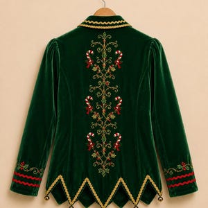Puede incluir: Una chaqueta de terciopelo verde oscuro con un dobladillo puntiagudo y peque&ntilde;as campanas doradas. La espalda presenta un intrincado bordado dorado, bastones de caramelo rojos y blancos y hojas de acebo. El cuello y el dobladillo tienen ribetes dorados.