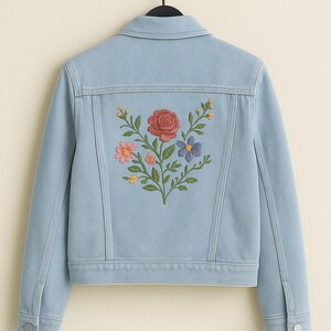 May include: A light blue denim jacket featuring a back panel embroidered with a floral arrangement of a large red rose, a pink flower, a blue flower, and small yellow buds with green leaves, complete with a collar, long sleeves, and metal buttons.