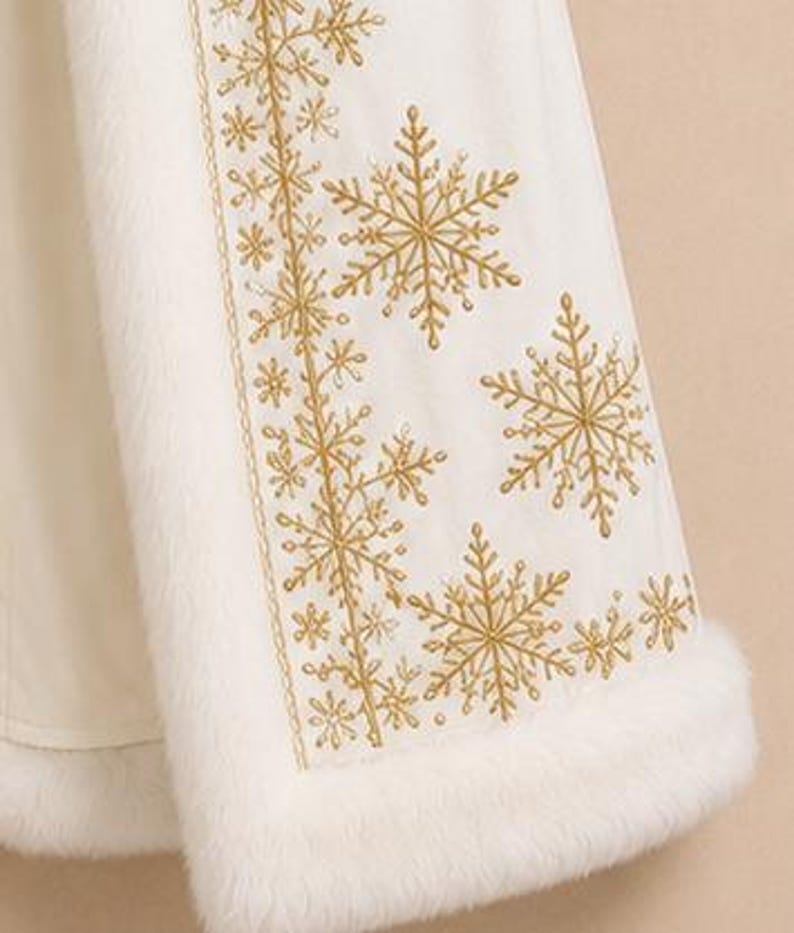 May include: A white cloak featuring a thick white faux fur trim along the edges and a vertical panel decorated with intricate gold embroidered snowflake patterns of varying sizes, creating a detailed winter-themed design on the fabric.