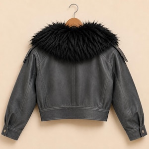 May include: A charcoal gray jacket featuring a prominent black faux fur collar. The jacket has long sleeves with buttoned cuffs, shoulder epaulets, and a cropped hemline. The back panel displays vertical seam detailing and a structured waistband.