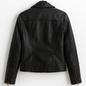 May include: Black faux leather jacket with a classic collar and zipper details. The back of the jacket is visible, showcasing vertical seams and a tailored fit. The jacket is hanging on a black hanger against a white background.