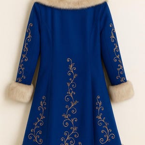 May include: A royal blue coat featuring a beige faux fur collar, cuffs, and hem. The coat is decorated with gold-colored swirling floral embroidery patterns along the sleeves and down the center back, hanging on a wooden hanger.