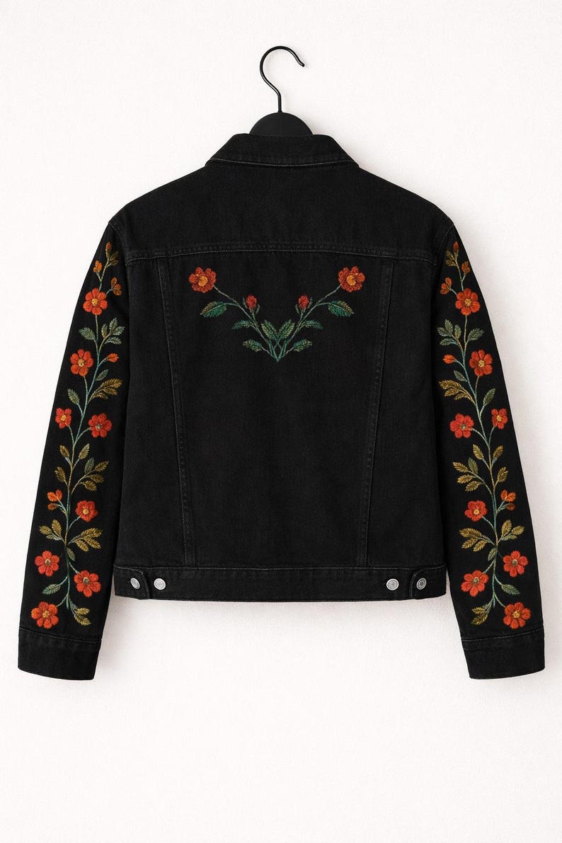 May include: A black denim jacket featuring long sleeves and a back panel decorated with embroidered floral patterns. The embroidery consists of orange flowers with green stems and leaves running down each sleeve and across the upper back.