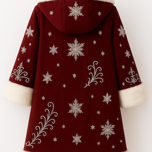 May include: A deep red hooded coat featuring white faux fur trim on the hood, cuffs, and hem. The coat is decorated with embroidered silver snowflake patterns and swirling vine motifs across the back and sleeves, hanging on a black hanger.