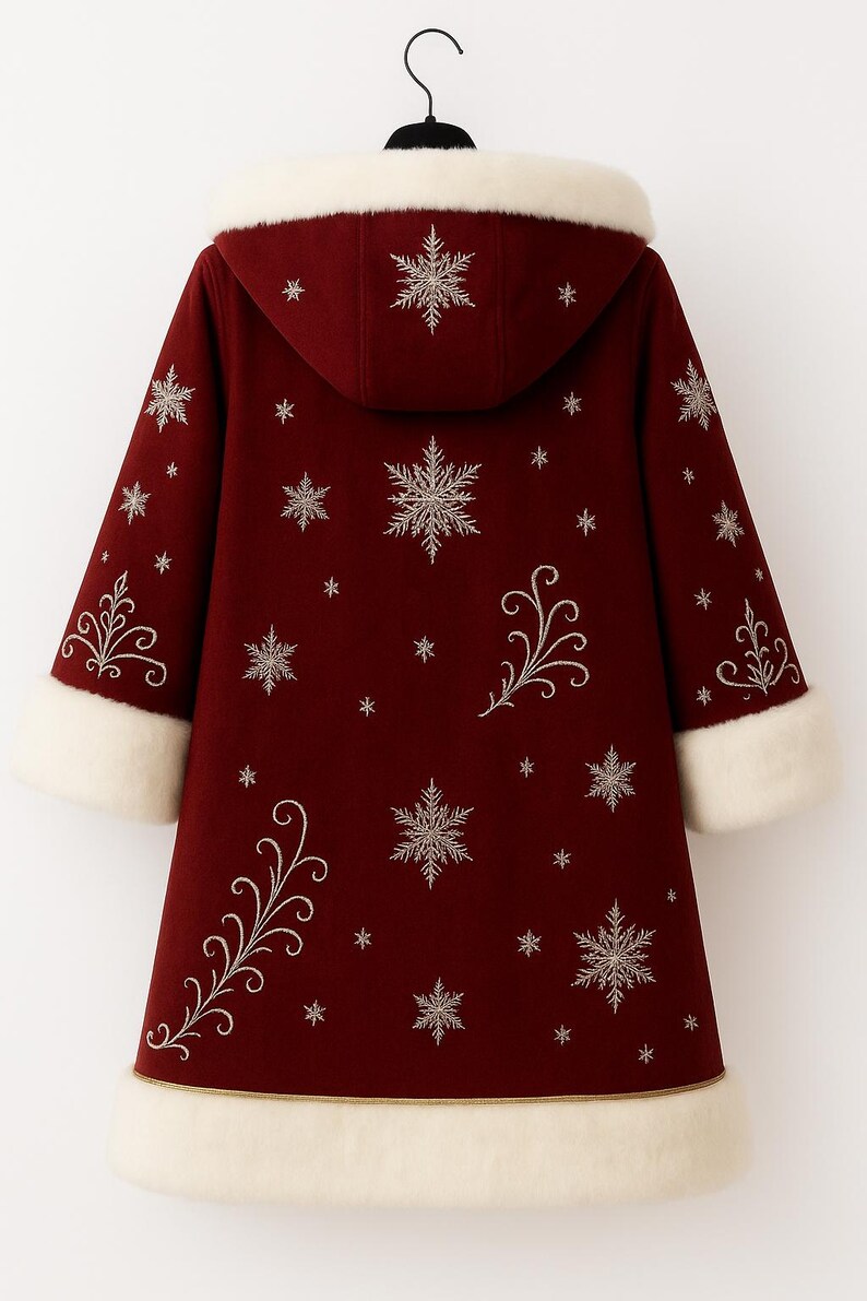 May include: A deep red hooded coat featuring white faux fur trim on the hood, cuffs, and hem. The coat is decorated with embroidered silver snowflake patterns and swirling vine motifs across the back and sleeves, hanging on a black hanger.