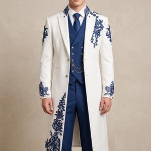 May include: A white long coat featuring dark blue floral embroidery on the lapels, shoulders, and lower front. The coat is worn over a dark blue vest with silver buttons and a chain, a white collared shirt, a dark blue tie, and blue trousers.