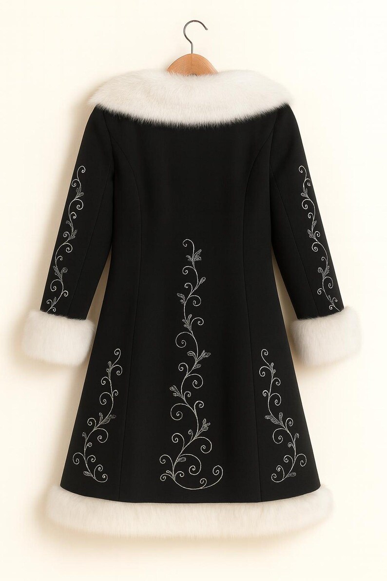 May include: A black coat featuring a white faux fur collar, white faux fur sleeve cuffs, and a white faux fur hem. The coat is decorated with silver embroidered floral vine patterns running down the center and along each sleeve.