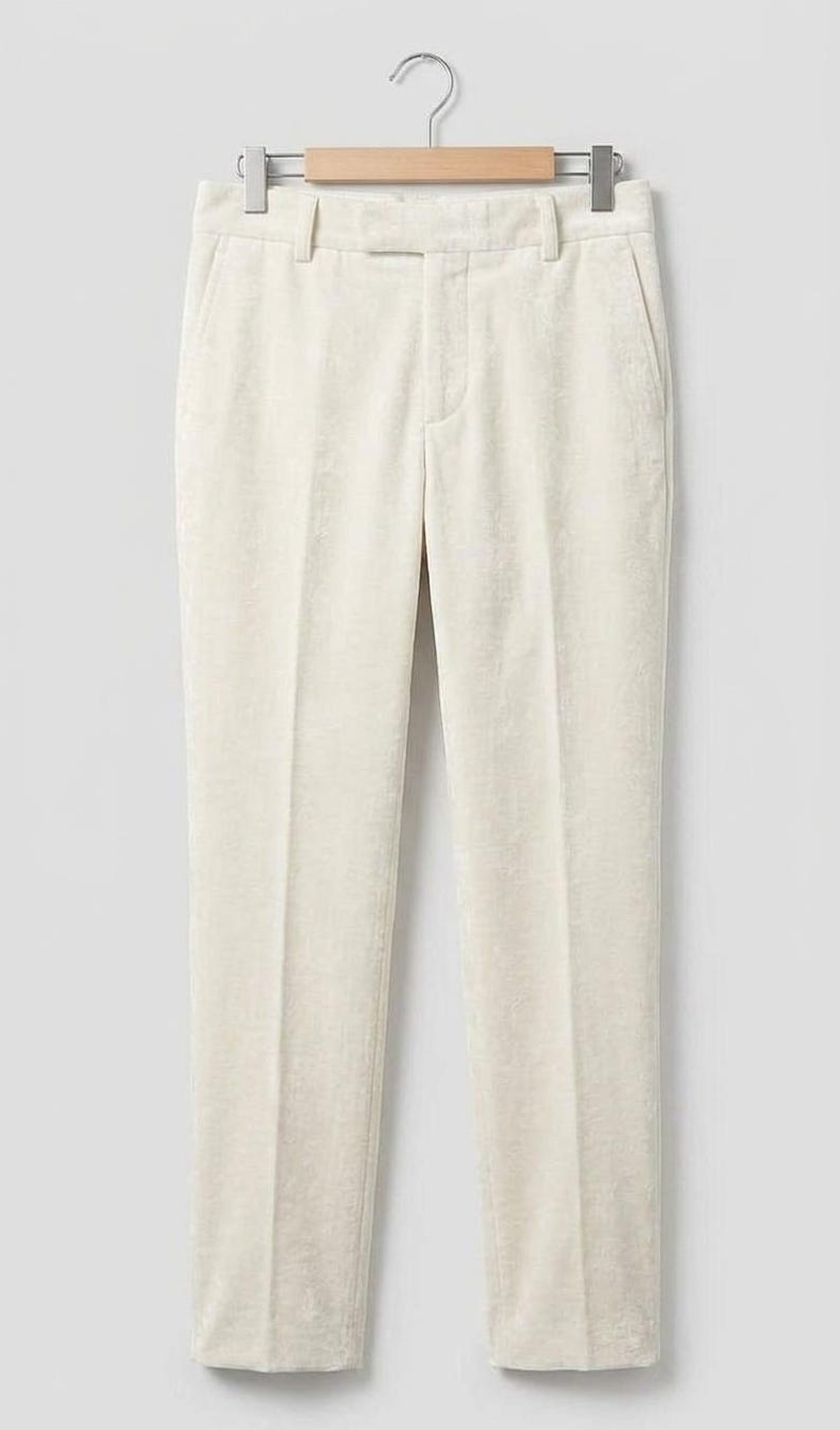 May include: Off-white trousers featuring a straight-leg cut, a structured waistband with belt loops, a front zipper fly with a button closure, and side pockets. The fabric has a subtle, soft-touch texture and a clean, tailored appearance.