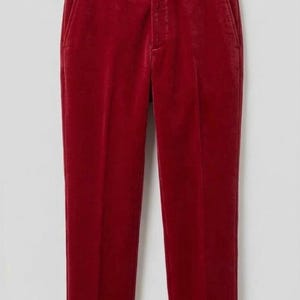 May include: Deep red velvet trousers featuring a structured waistband with a single button closure, belt loops, and a front zipper fly. The pants have a straight-leg cut with a visible pressed crease running down the center of each leg.
