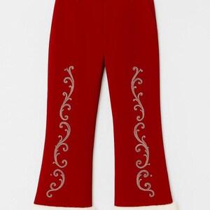 Puede incluir: Pantalones de color rojo intenso con silueta de pierna acampanada y ribete de piel sint&eacute;tica blanca en los dobladillos. La parte delantera de cada pierna est&aacute; decorada con un intrincado patr&oacute;n de bordado de filigrana.