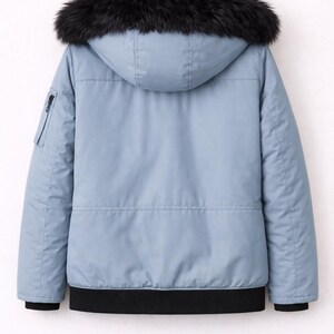 Pode incluir: Casaco de inverno azul claro com capuz forrado a p&ecirc;lo sint&eacute;tico preto. O casaco tem um bolso com z&iacute;per na manga esquerda e uma bainha canelada preta. O casaco est&aacute; pendurado num cabide de madeira.