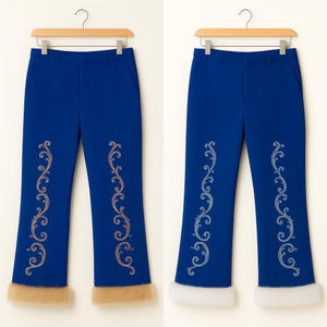 Puede incluir: Dos pantalones azul real colgados en perchas de madera. Cada par presenta un patr&oacute;n de bordado de enredaderas verticales en las piernas y un borde grueso de piel sint&eacute;tica en el dobladillo. Un par tiene bordado y piel beige, el otro es blanco.
