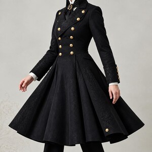 May include: A black double-breasted coat featuring a high collar, long sleeves with buttoned cuffs, and a flared skirt. The coat is adorned with gold-toned buttons and a subtle tonal floral pattern. It is worn over a white collared shirt and black trousers.