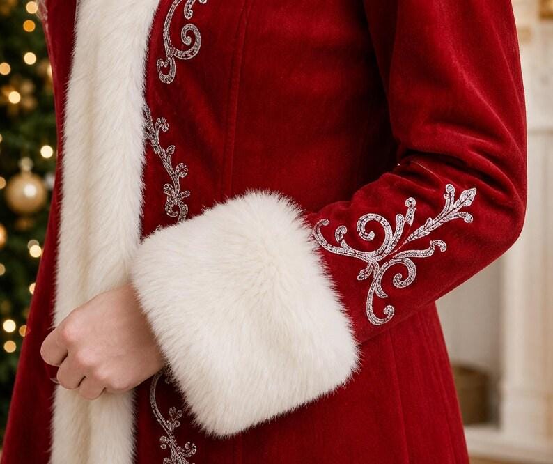 May include: A deep red velvet coat featuring white faux fur trim along the front opening and cuffs. The garment is decorated with intricate silver embroidery in a swirling pattern along the front edge and on the outer sleeve near the cuff.