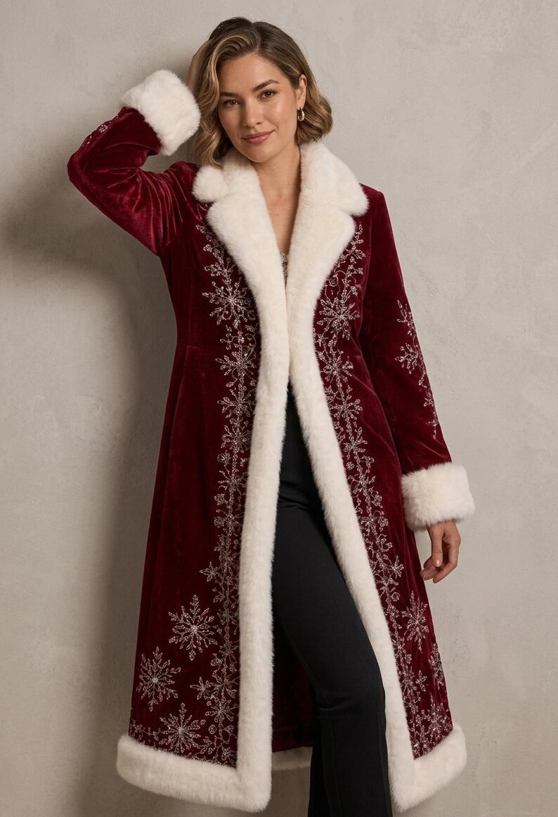 May include: A long, deep red velvet coat featuring white faux fur trim on the collar, cuffs, and hem. The coat is decorated with intricate silver embroidered snowflake patterns along the front panels and lower sections of the garment.