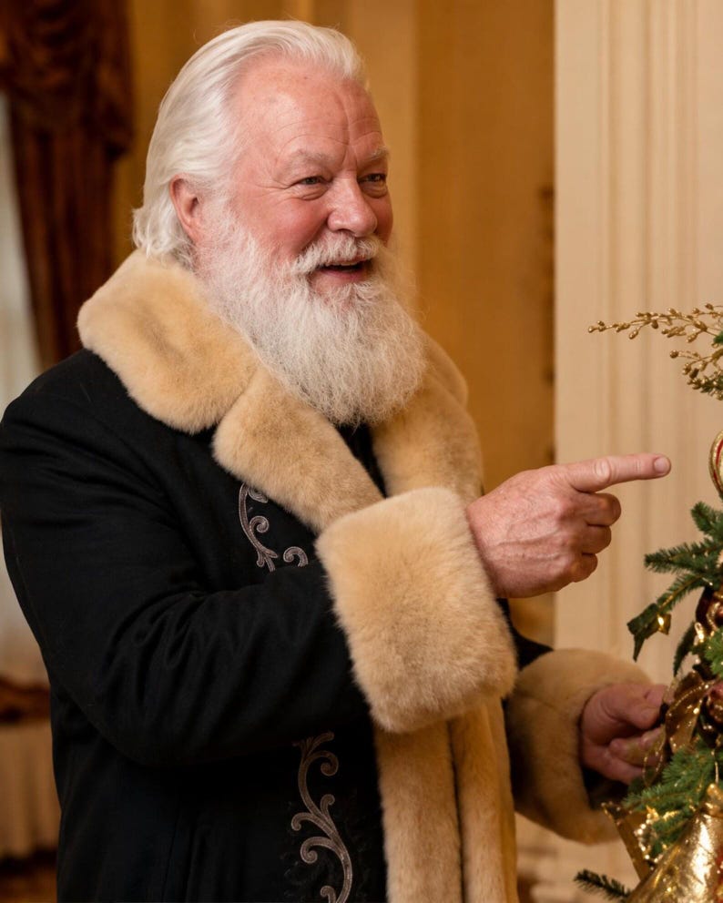 May include: A person with white hair and a full white beard wearing a black coat with a thick beige faux fur collar and cuffs. The coat features intricate silver embroidery along the front opening. The person is pointing toward a decorated tree.