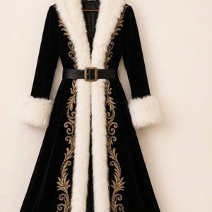 May include: A long black velvet coat featuring a thick white faux fur collar and cuffs. The coat is adorned with intricate gold embroidery along the front opening and hem, and includes a black leather belt with a rectangular metal buckle.