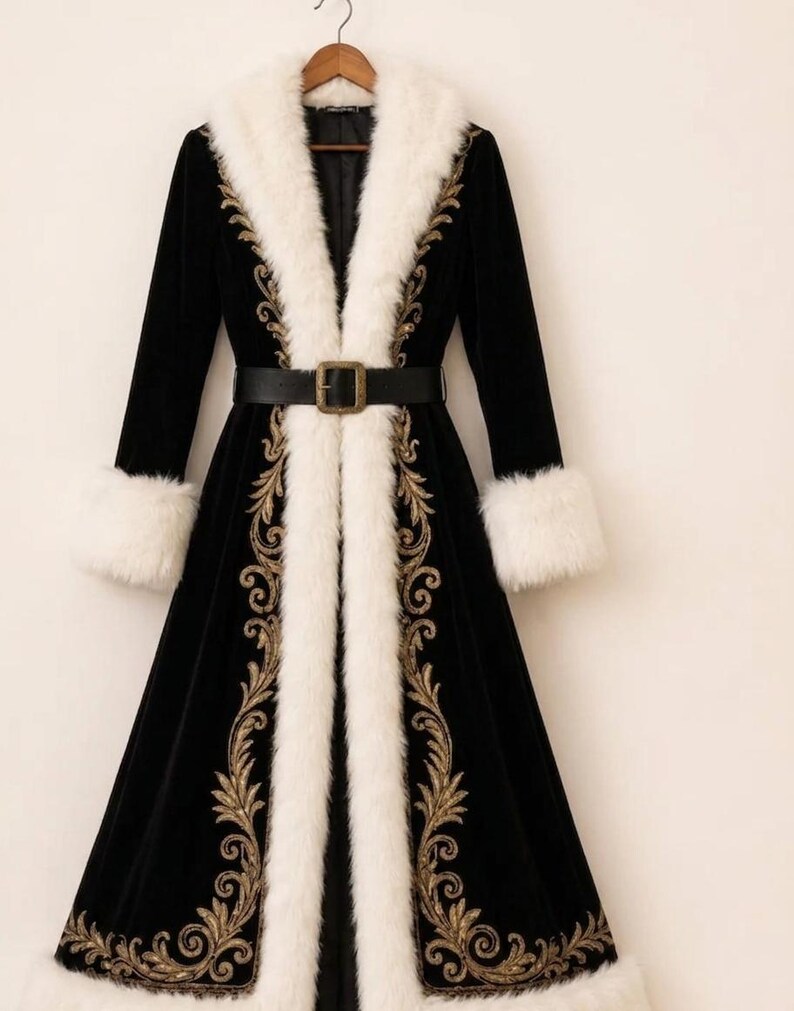 May include: A long black velvet coat featuring a thick white faux fur collar and cuffs. The coat is adorned with intricate gold embroidery along the front opening and hem, and includes a black leather belt with a rectangular metal buckle.
