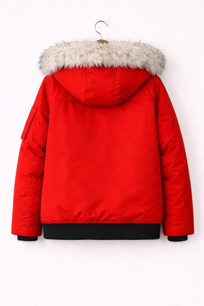 May include: A red winter jacket with a hood and a faux fur trim. The jacket has a black ribbed hem and cuffs, and a small pocket on the left sleeve. The jacket is hanging on a hanger.