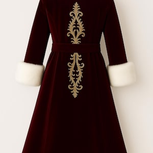 May include: A deep burgundy velvet coat featuring a white faux fur collar, white faux fur cuffs, and a white faux fur hem. The back of the coat is decorated with a vertical gold embroidered filigree pattern and includes a matching velvet waist belt.