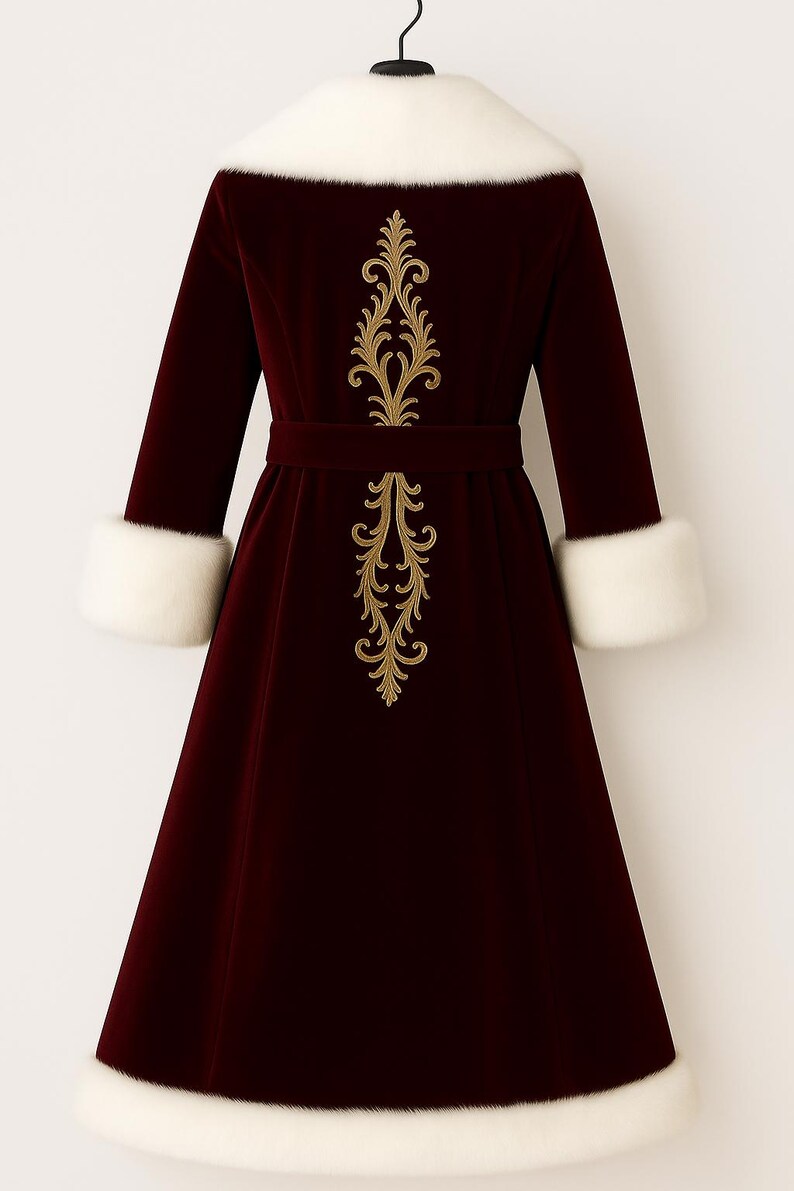 May include: A deep burgundy velvet coat featuring a white faux fur collar, white faux fur cuffs, and a white faux fur hem. The back of the coat is decorated with a vertical gold embroidered filigree pattern and includes a matching velvet waist belt.