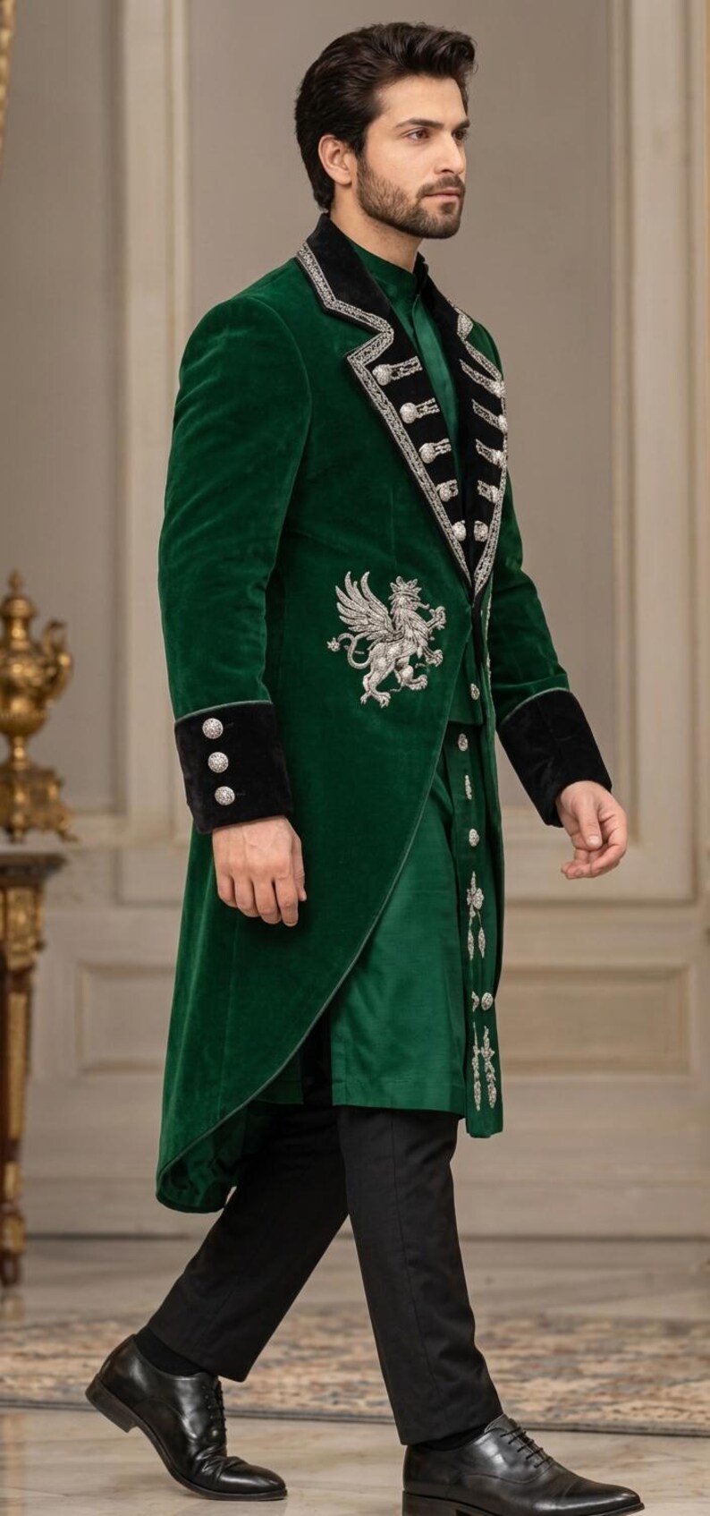May include: A deep green velvet long coat featuring black velvet lapels and cuffs, adorned with silver metallic embroidery of a griffin on the chest and silver buttons. The coat is worn over a matching green tunic and solid black trousers.