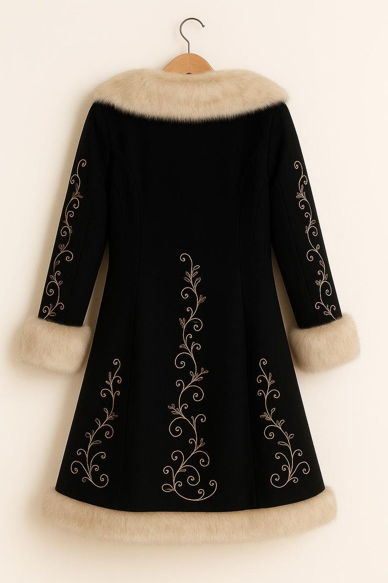 May include: A black coat featuring a beige faux fur collar, cuffs, and hem. The coat is decorated with gold-colored embroidered vine patterns running down the center back and along the outer length of each sleeve, hanging on a wooden hanger.