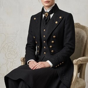 May include: A black long-sleeved coat featuring gold-toned buttons, a matching waistcoat, and intricate tonal embroidery on the lapels and cuffs. The ensemble includes a white collared shirt and a black neck accessory with a central dark gemstone detail.