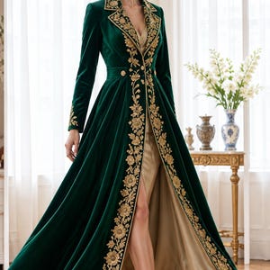 May include: A floor-length dark green velvet coat featuring long sleeves, a wide lapel, and intricate gold floral embroidery along the front edges and cuffs. The coat is worn over a solid beige dress with a high front slit and gold high heels.
