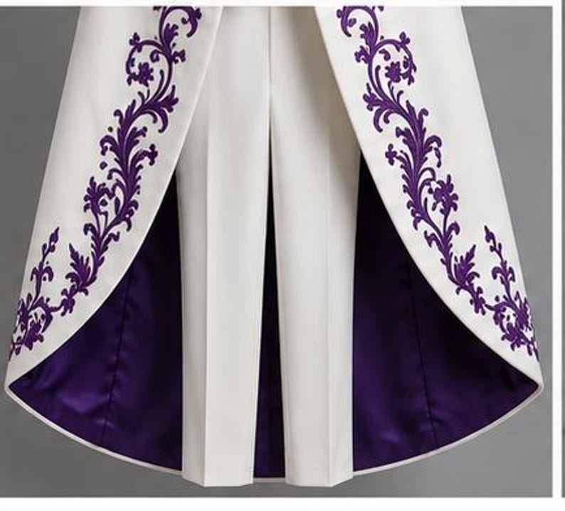 May include: A white coat with a high-low hemline featuring deep purple floral embroidery along the front edges. The interior lining of the coat is a solid deep purple satin, and it is worn over a pair of matching white tailored trousers.
